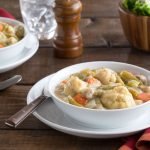White bowl of Chicken and Dumplings on a dinner table